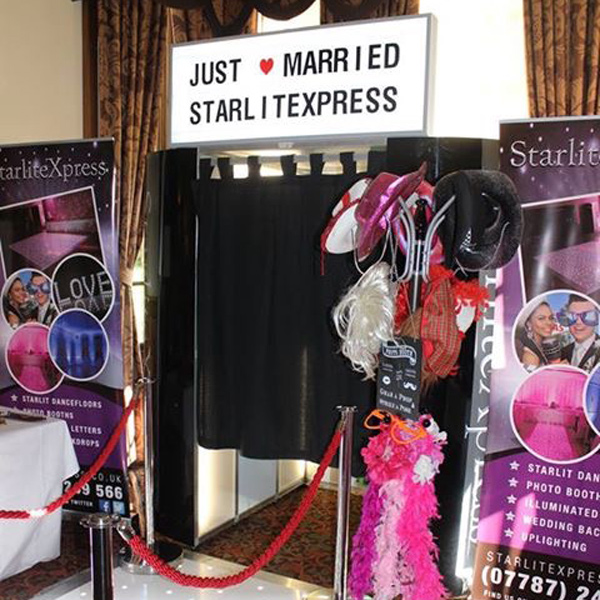 Oval photo booth with light up sign between two banners and props